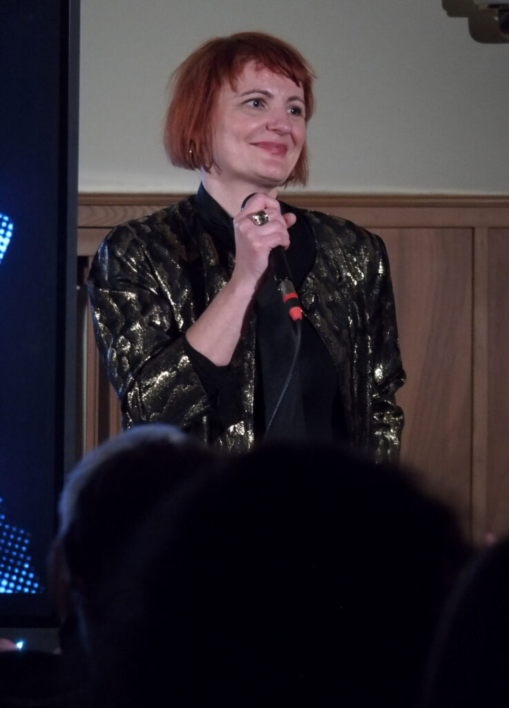 Die Moderatorin des FLINTA Festes Anita Tokic blickt zufrieden ins Publikum.