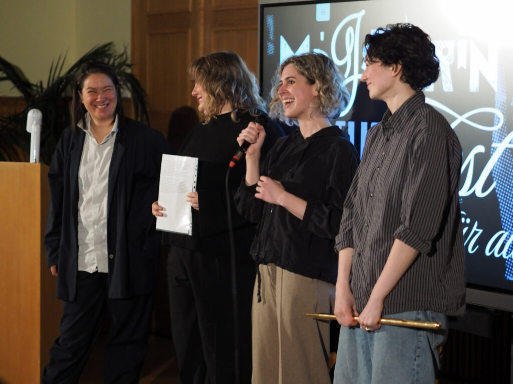 Ein Pink Noise Mitglied spricht hocherfreut über den Gewinn der großen, goldenen Nadel zum Publikum.